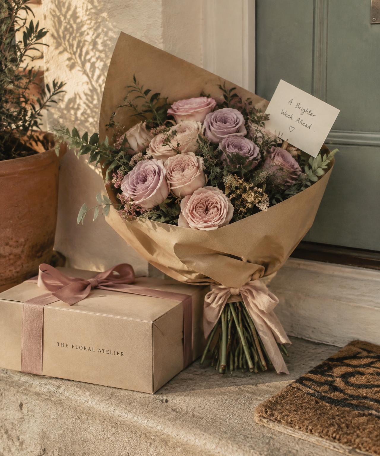 Bouquet of pink and lavender roses with a handwritten note on a doorstep
